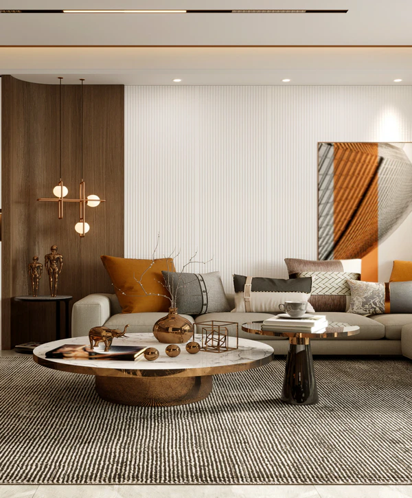 A luxurious modern living room featuring a round marble coffee table with bronze decor, a beige sofa with warm-toned pillows, and modern pendant lighting, showcasing a whole home remodeling project in Cupertino.
